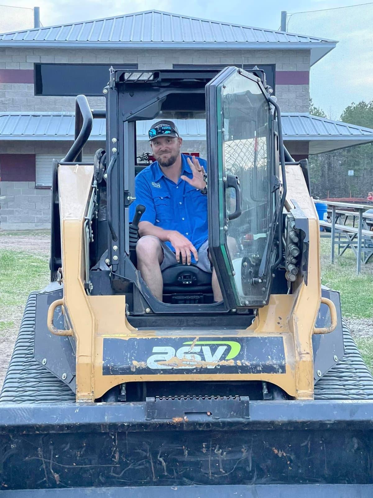Jonathon Bird, owner of Houston County Mulching, waving from the cab of a tracked skid steer